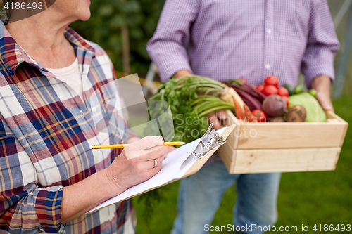 Image of senior couple with box of vegetables at farm