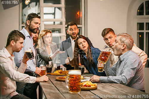 Image of Group of friends enjoying evening drinks with beer