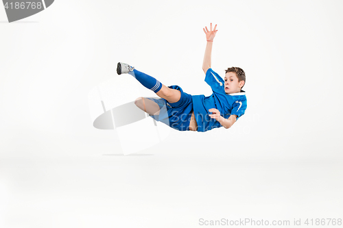 Image of Young boy with soccer ball doing flying kick