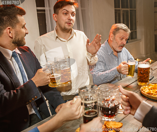 Image of Group of friends enjoying evening drinks with beer