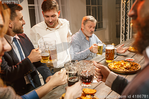 Image of Group of friends enjoying evening drinks with beer