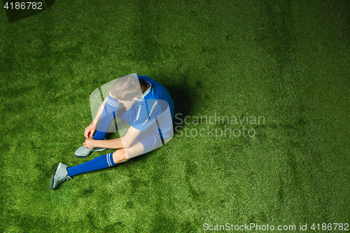 Image of Boy soccer player sitting on greeb grass