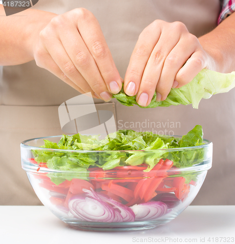 Image of Cook is tearing lettuce while making salad