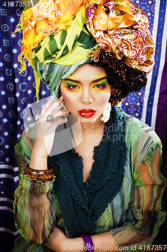 Image of beauty bright woman with creative make up, many shawls on head l