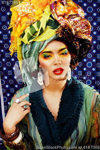 Image of beauty bright woman with creative make up, many shawls on head l