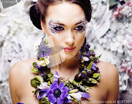 Image of floral face art with anemone in jewelry, sensual young brunette 