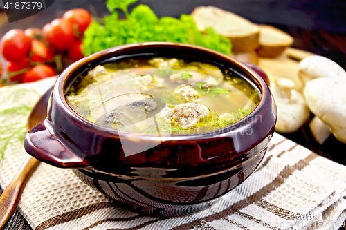 Image of Soup with meatballs and mushrooms in pottery on napkin