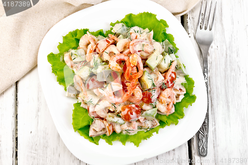 Image of Salad with shrimp and avocado in plate on board top