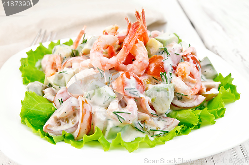 Image of Salad with shrimp and avocado in white plate on board