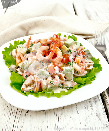 Image of Salad with shrimp and tomatoes in white plate on board