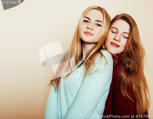 Image of Two young girlfriends in winter sweaters indoors having fun. Lif