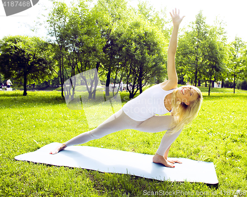 Image of young pretty blond girl doing yoga in green sunny park at morning, lifestyle sport people concept