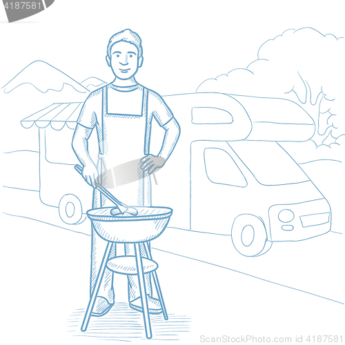 Image of Man having barbecue in front of camper van.