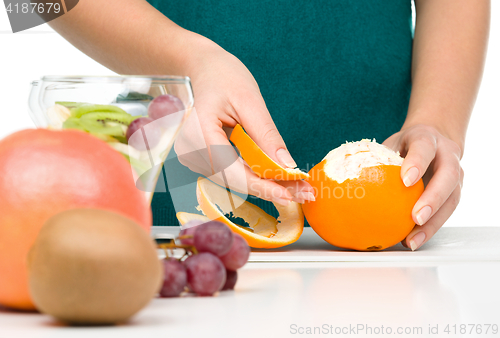 Image of Cook is peeling orange for fruit dessert