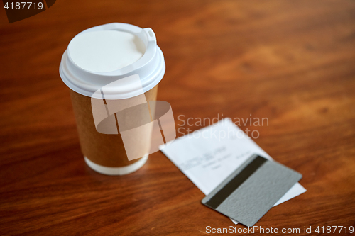 Image of coffee in paper cup, bill and credit card on table