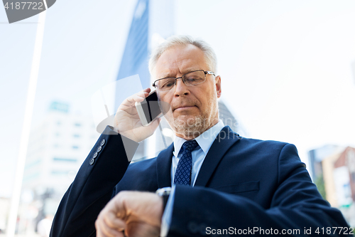 Image of senior businessman calling on smartphone in city