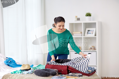 Image of woman packing travel bag at home or hotel room