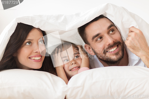 Image of happy family lying in bed under blanket at home