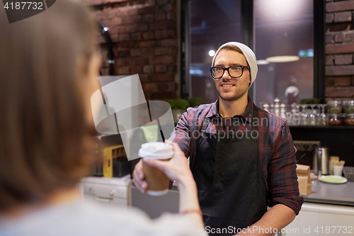 Image of seller giving coffee cup to woman customer at cafe