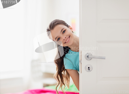 Image of happy smiling beautiful girl behind door at home