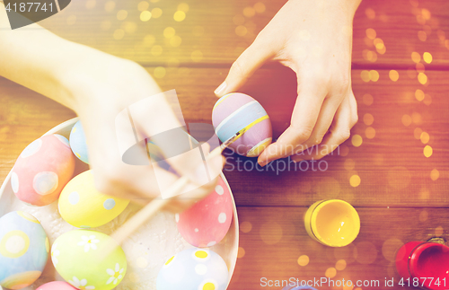 Image of close up of woman hands coloring easter eggs