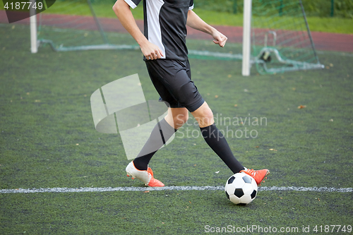 Image of soccer player playing with ball on football field