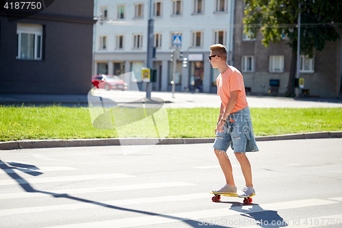 Image of teenage boy on skateboard crossing city crosswalk