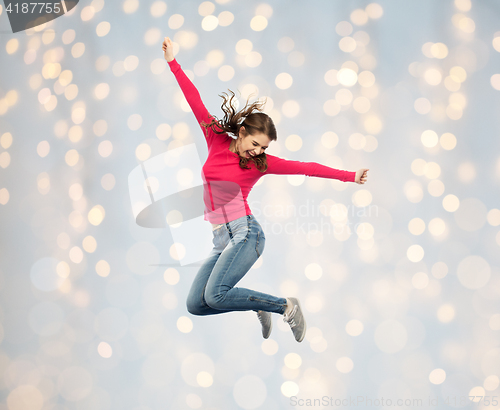 Image of smiling young woman jumping over holidays lights