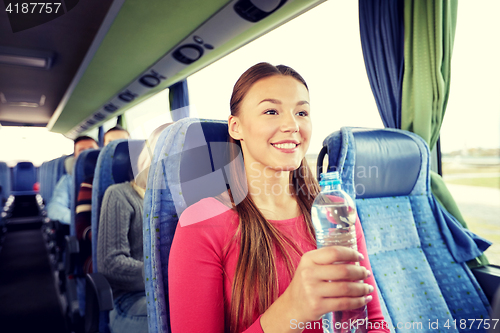 Image of happy young woman with water bottle in travel bus