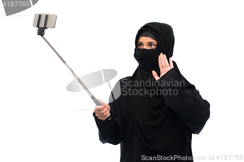 Image of muslim woman in hijab taking selfie by smartphone