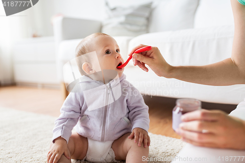 Image of mother with spoon feeding little baby at home