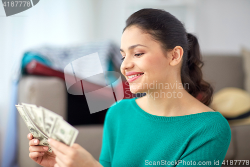 Image of happy woman with money planning her travel at home