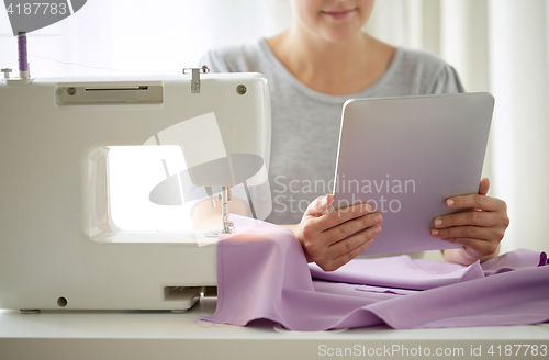 Image of tailor with sewing machine, tablet pc and fabric