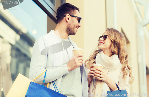 Image of happy couple with shopping bags and coffee in city