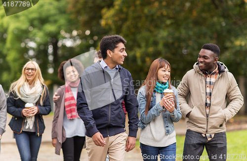 Image of happy friends walking along autumn park