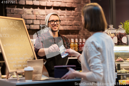 Image of happy barman and woman paying money at cafe