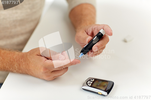 Image of senior man with glucometer checking blood sugar