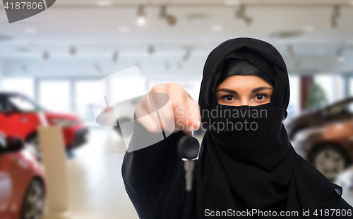 Image of muslim woman in hijab with car key over car show