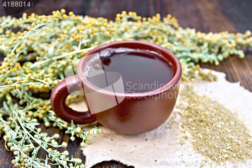 Image of Tea with wormwood in brown cup on board