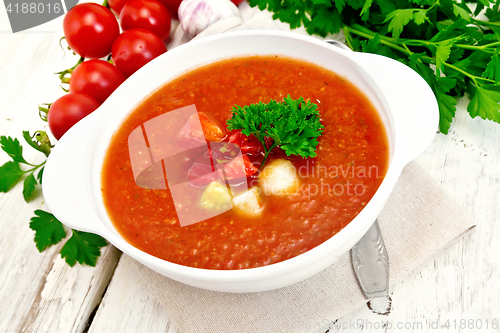 Image of Soup tomato in white bowl with vegetables and parsley on board