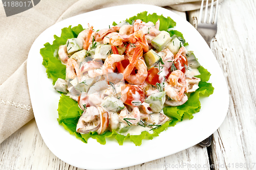 Image of Salad with shrimp and tomatoes in plate on board