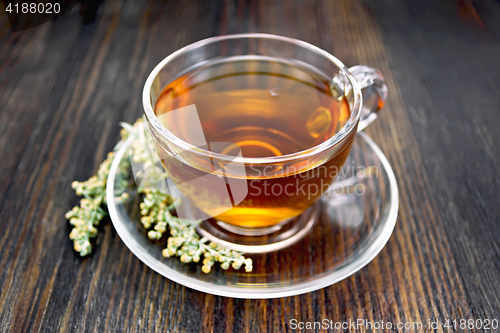 Image of Tea with gray wormwood in glass cup on board