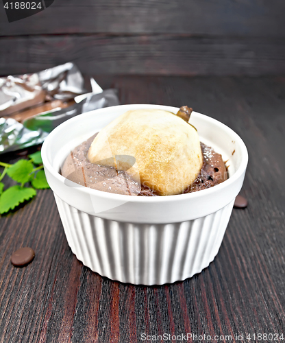 Image of Cake with chocolate and pear in white bowl on dark board