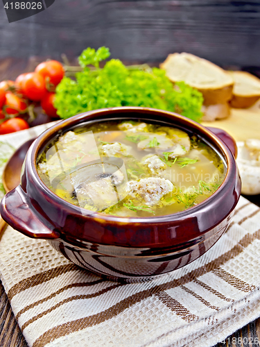 Image of Soup with meatballs and mushrooms in clay bowl on napkin