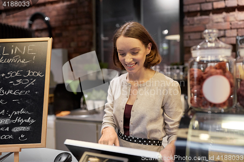 Image of happy woman or barmaid with cashbox at cafe