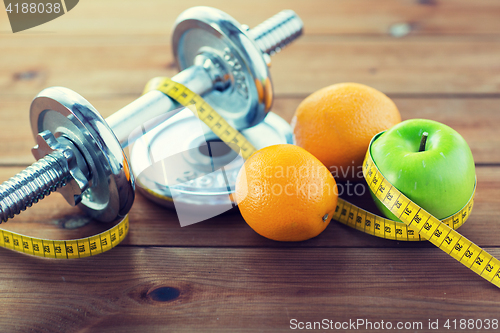 Image of close up of dumbbell, fruits and measuring tape