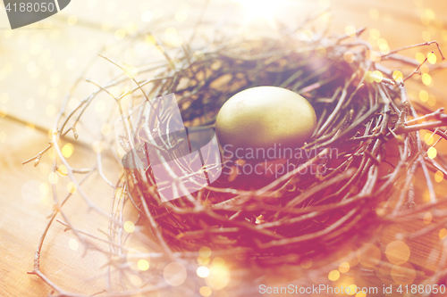 Image of close up of golden easter egg in nest on wood