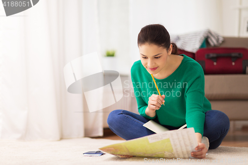 Image of woman with notebook and travel map at home