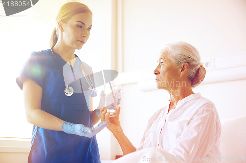 Image of nurse giving medicine to senior woman at hospital