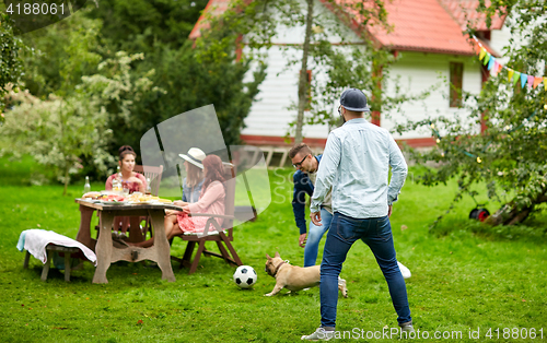 Image of friends playing football with dog at summer garden